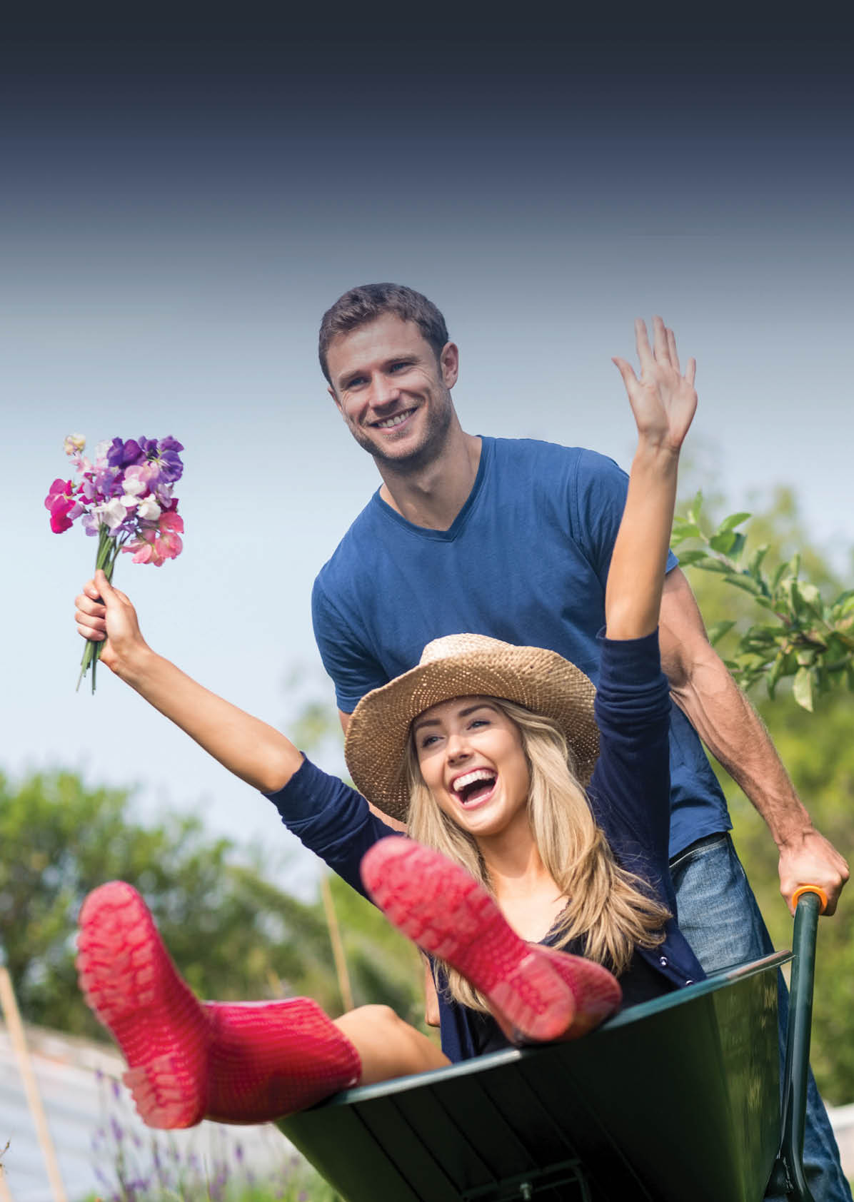 Man pushing his girlfriend in a wheelbarrow at home in the garden