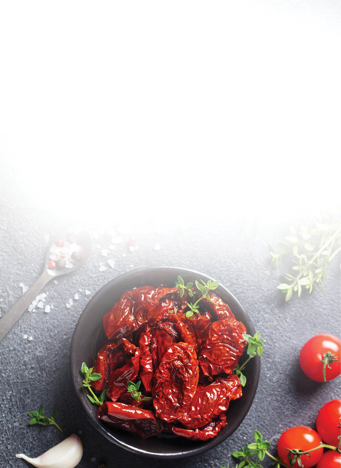 Sun dried tomatoes with fresh herbs and spices. Slate background. Top view. Copy space.