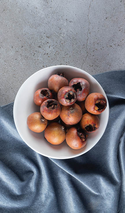 Healthy medlar fruits in a white bowl placed on stone background. High quality photo