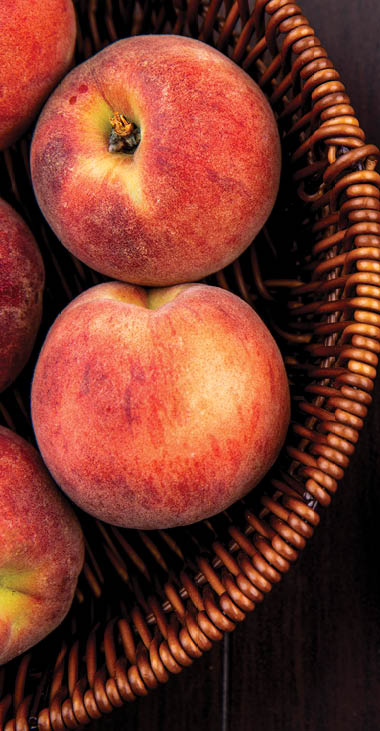 top view of delicious and juicy peaches on a bucket on a wooden background
