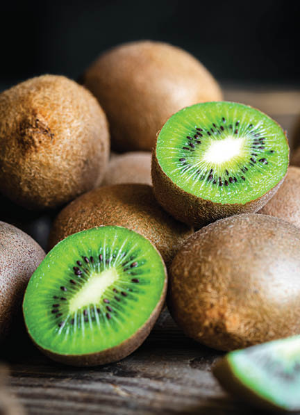 Ripe fruits of kiwi cut and whole on a wooden background, close -up.