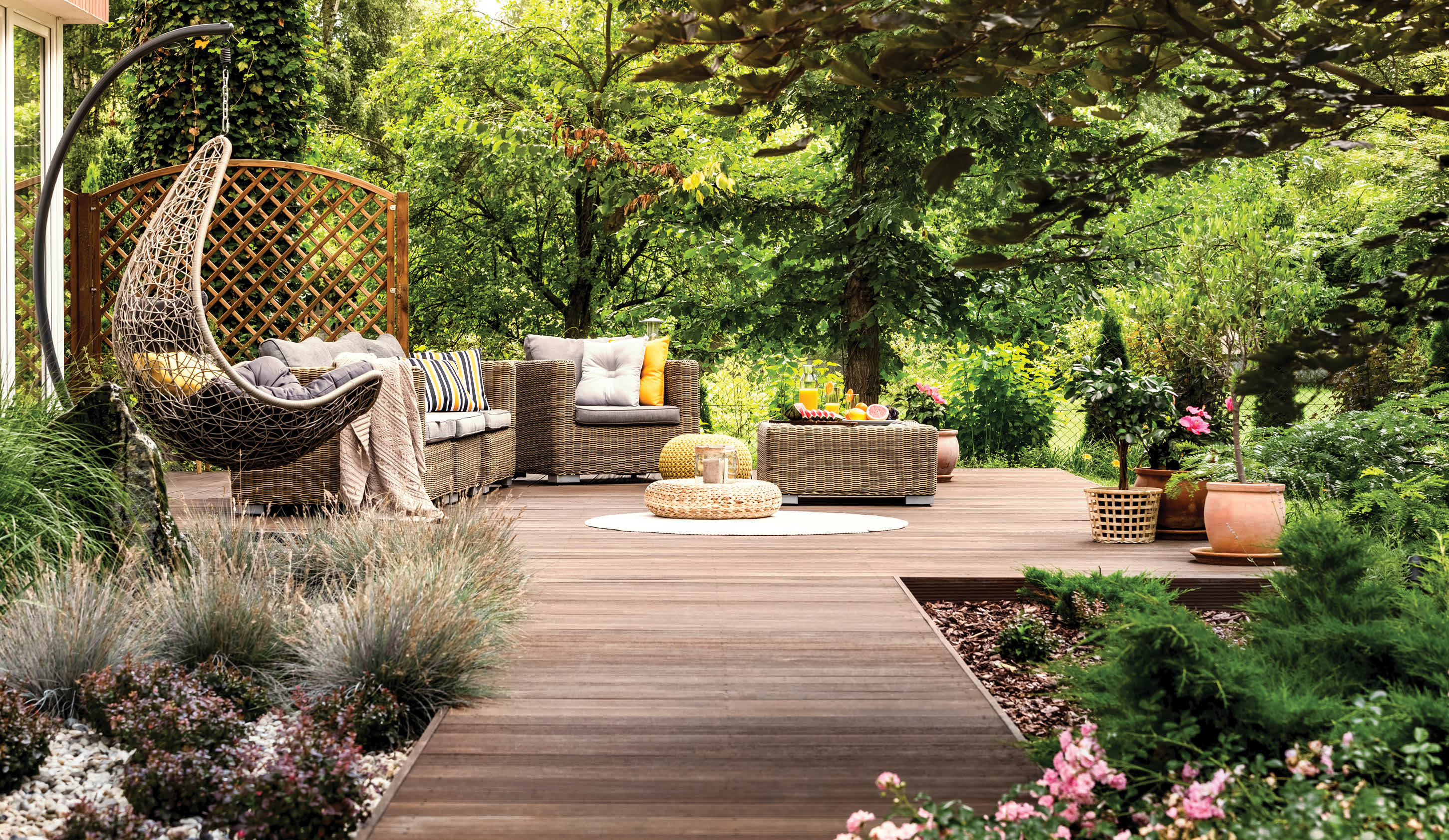 Beautiful wooden terrace with garden furniture surrounded by greenery on a warm, summer day