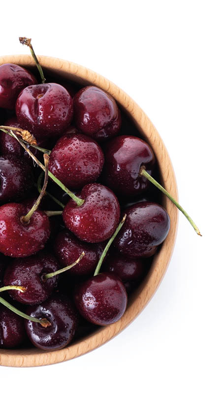 Fresh cherries with water drops in wooden bowl isolated on white background