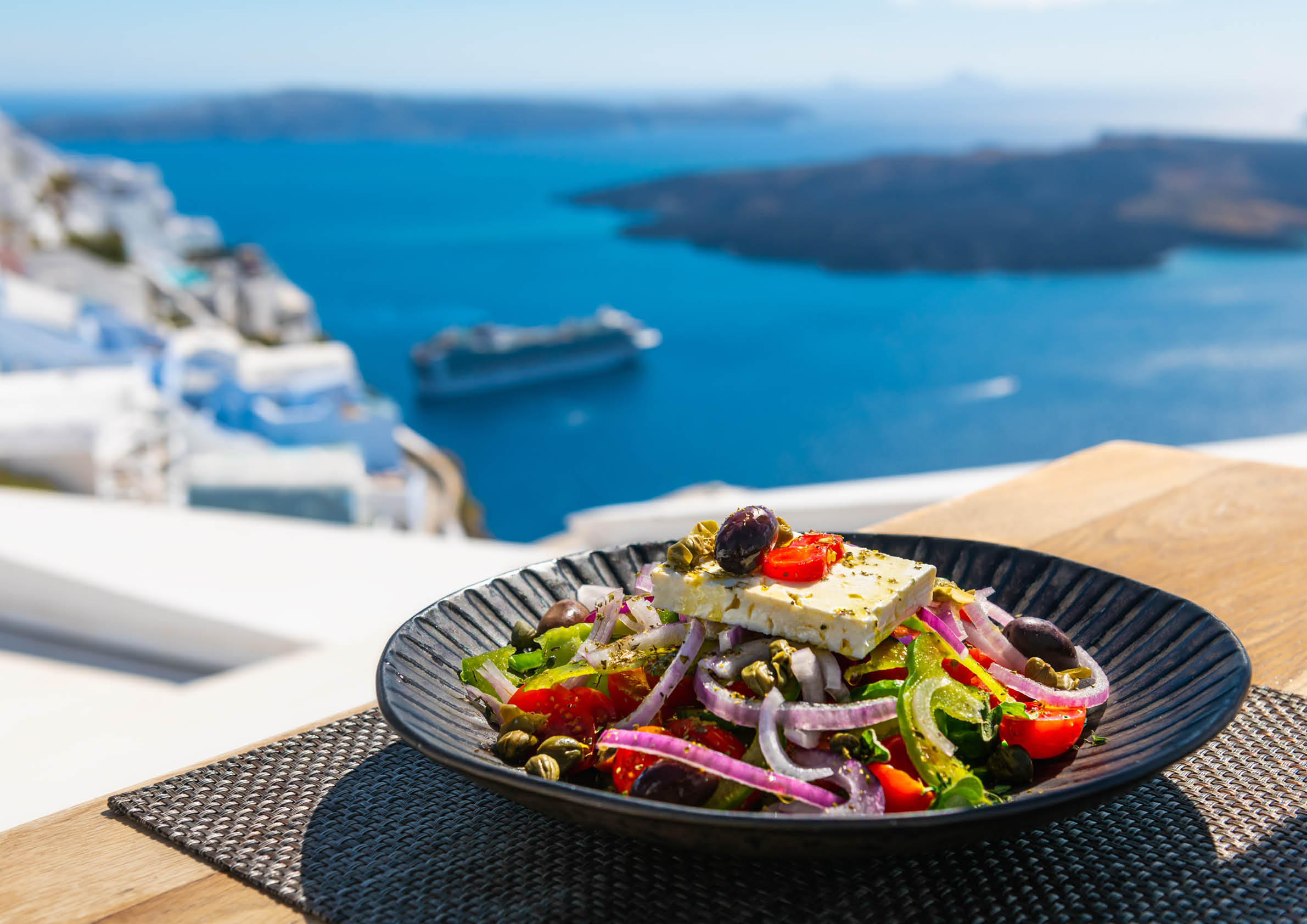 Greek salad with beautiful sea view in Santorini island, Greece. National greek cuisine concept. Travel and vacation