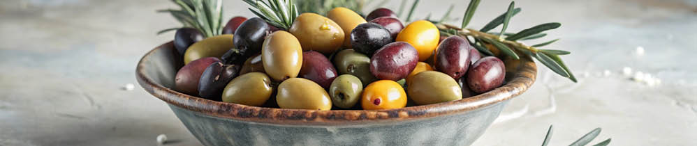 A bowl of assorted olives with rosemary sprigs on a light textured background.