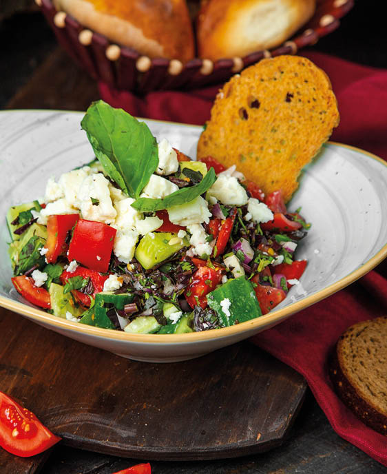 fresh salad with cheese and herbs and a crisp slice of bread